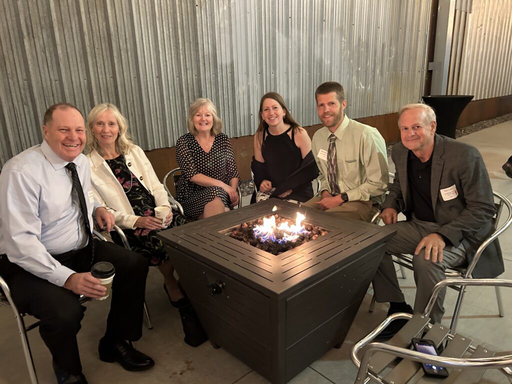 Group of benefit guests seated around a campfire