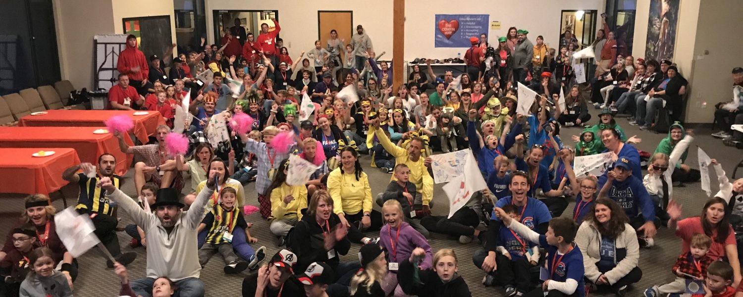 Super large group shot of families all dressed up in team costumes cheering at the camera
