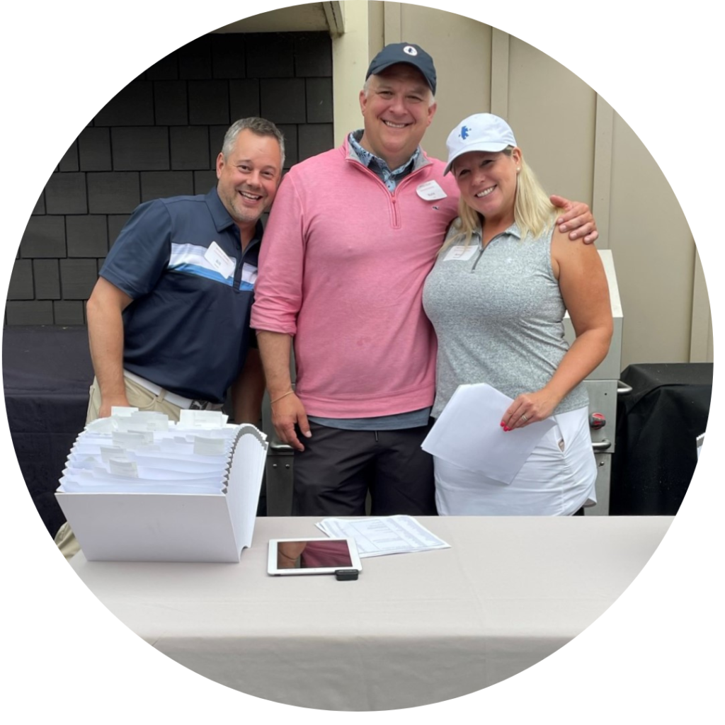 Three volunteers staffing registration at the Whole Heart Golf Tournament