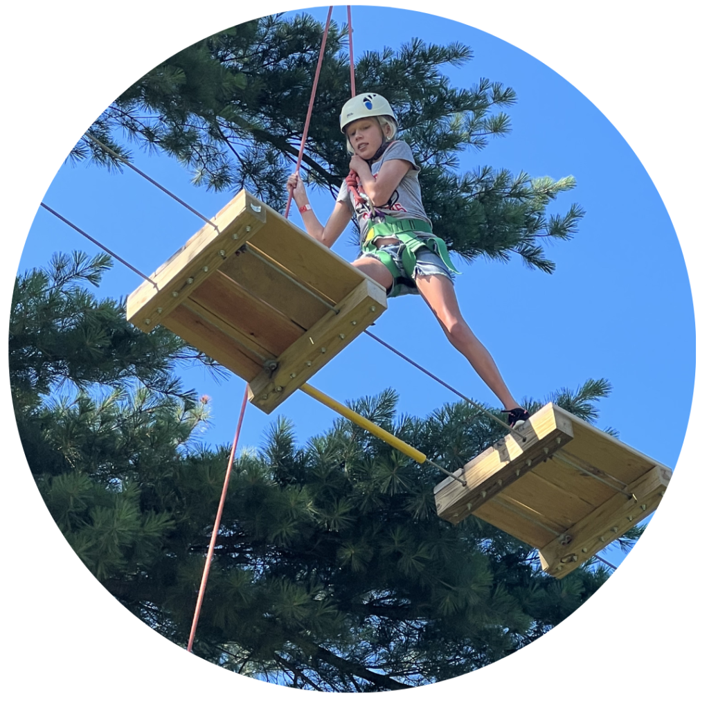 Camper with a heltmet doing high ropes course