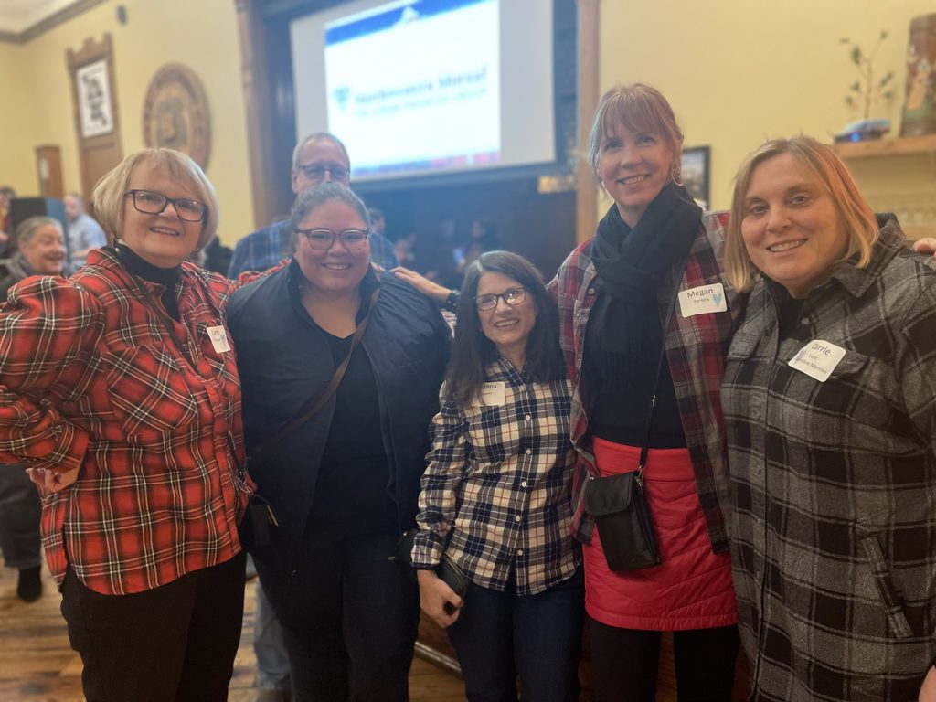 A group of event attendees huddle together for a photo, smiling at the camera
