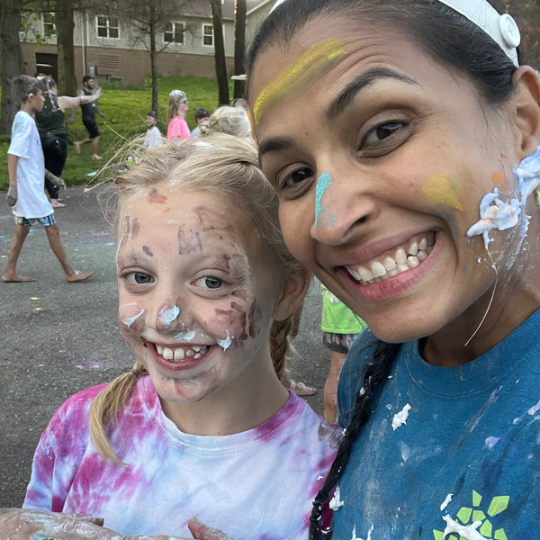 Camper and volunteer with shaving cream and colored powder on their faces and shirts