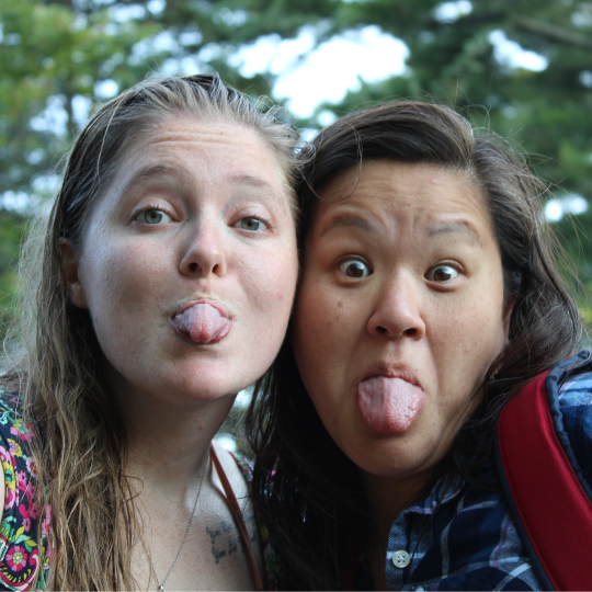 Two volunteers playfully sticking their tongues out