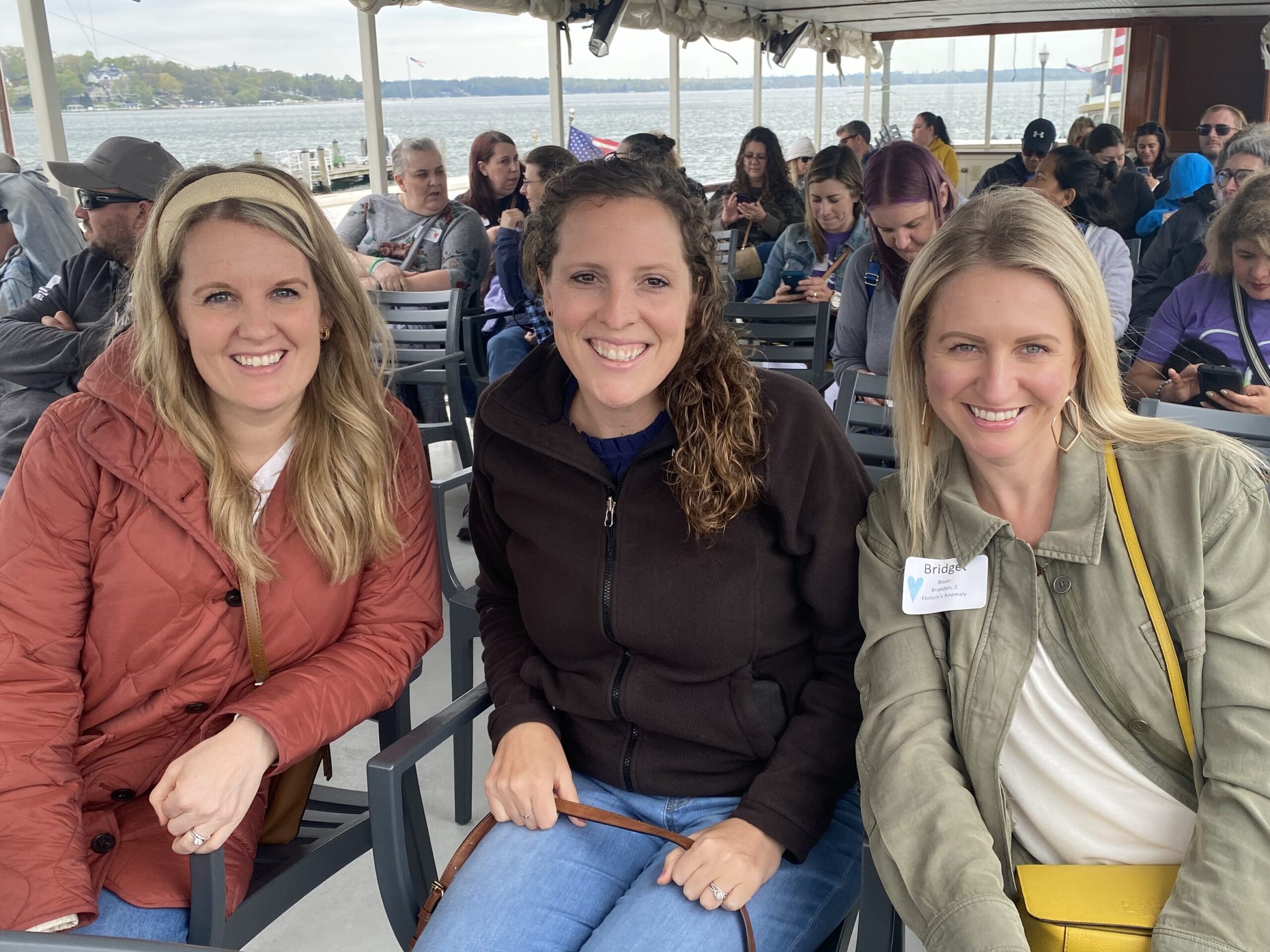 Three heart moms smile for a photo while seated onboard a Lake Geneva boat cruise.
