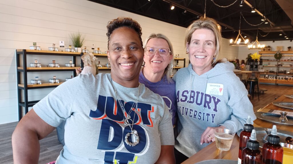 Three heart moms group up for a photo while at a custom candle making shop.