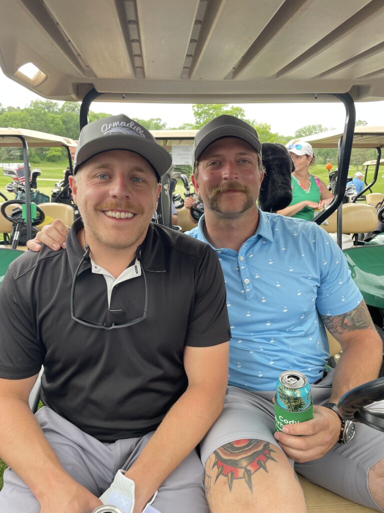 Two golfers seated in a golf cart