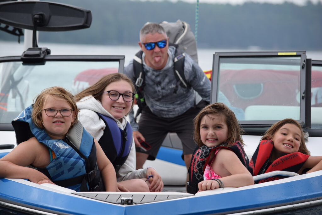 Group of campers on a speedboat and a volunteer nurse sticking out their tongue