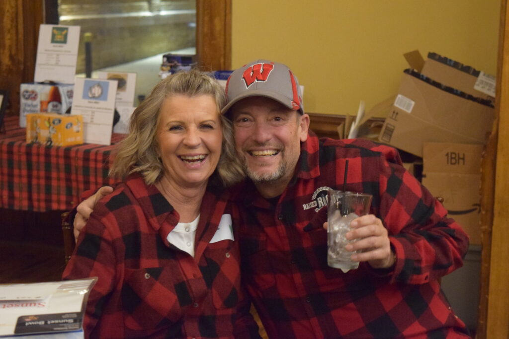 Two guests in red and black flannel smile at the camera