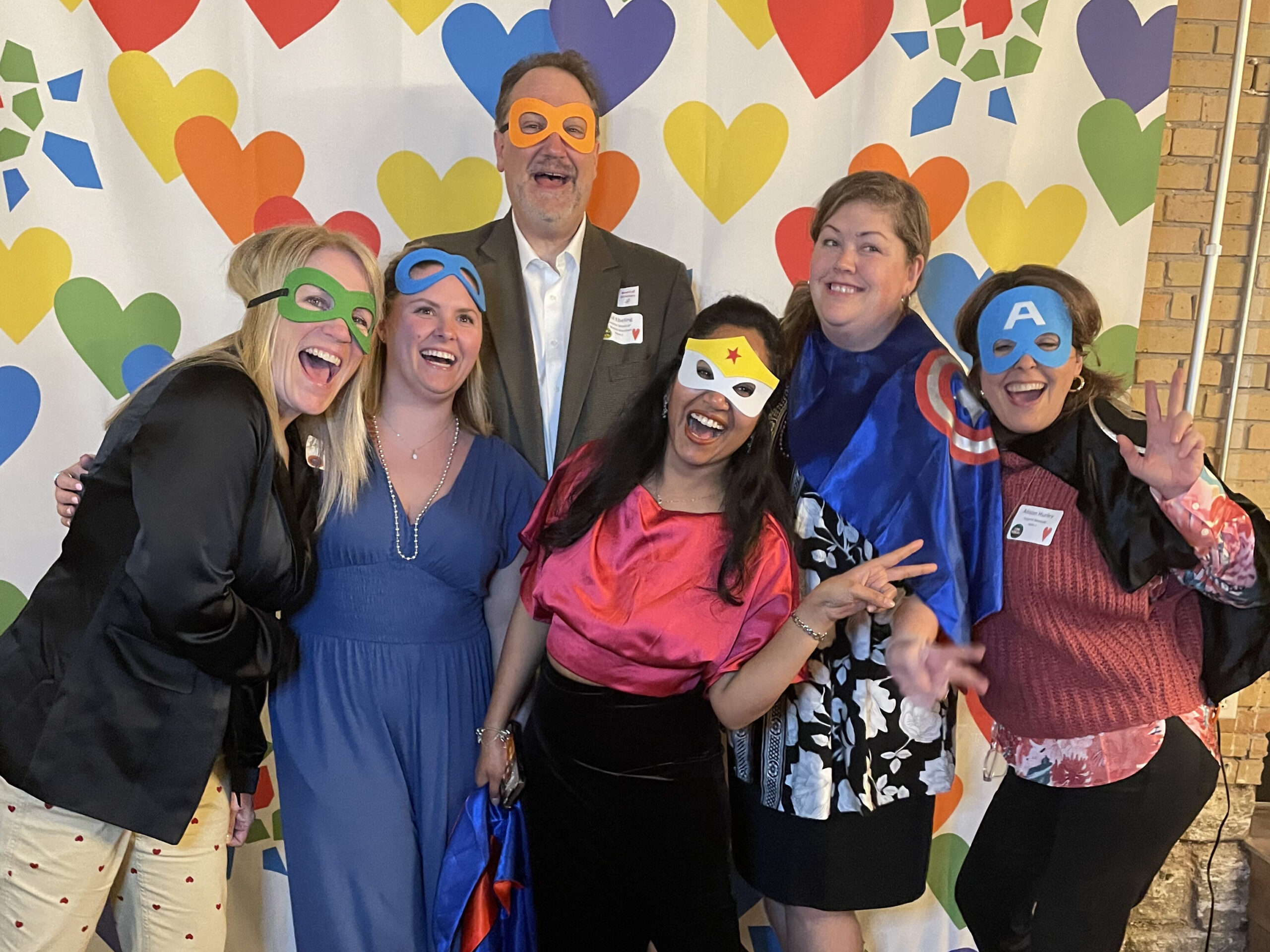 Benefit guests pose while wearing superhero capes and masks