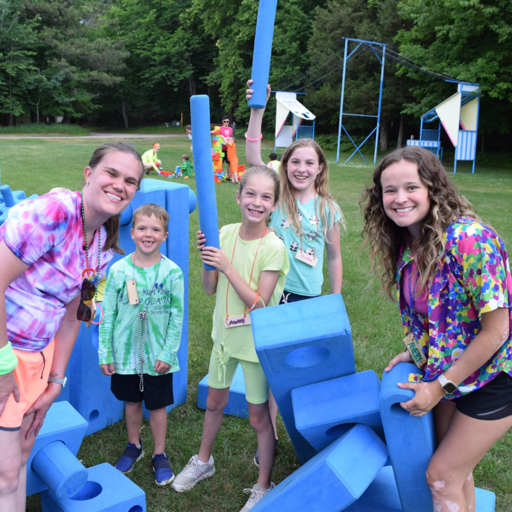 Campers and volunteers playing outside with large foam building pieces