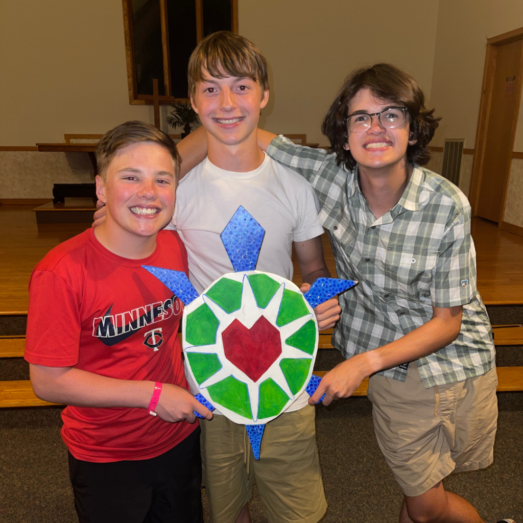 Three teenage campers holding the Odayin turtle logo