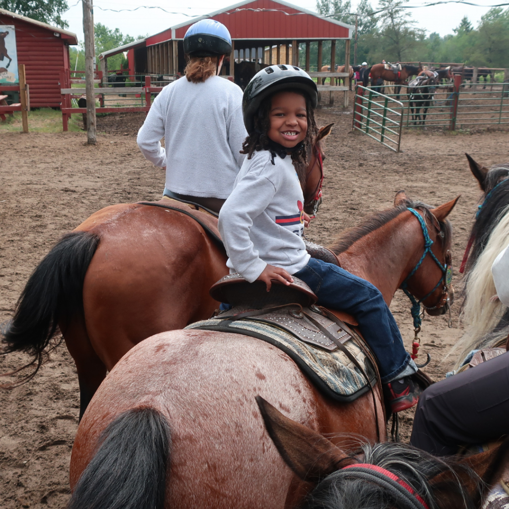 A camper looking over their shoulder while riding a horse