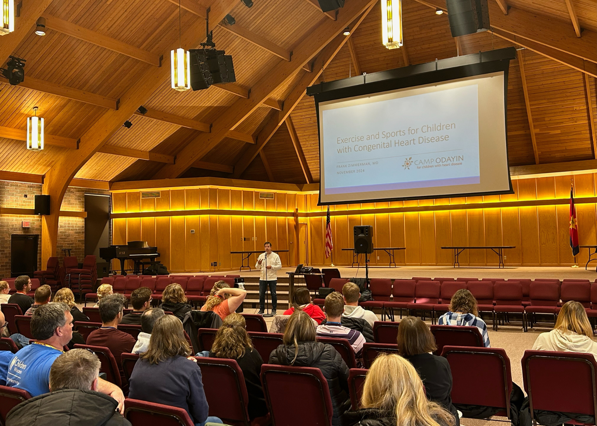 Audience of parents looking at a screen and doctor speaking