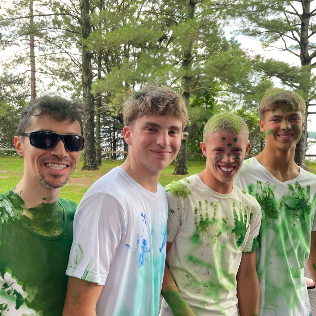 Volunteer and three campers with green paint on white shirts & faces